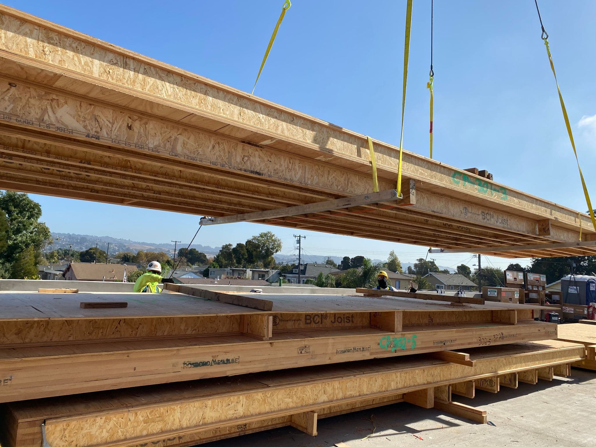 Crane lifting cassette panel at urban construction site