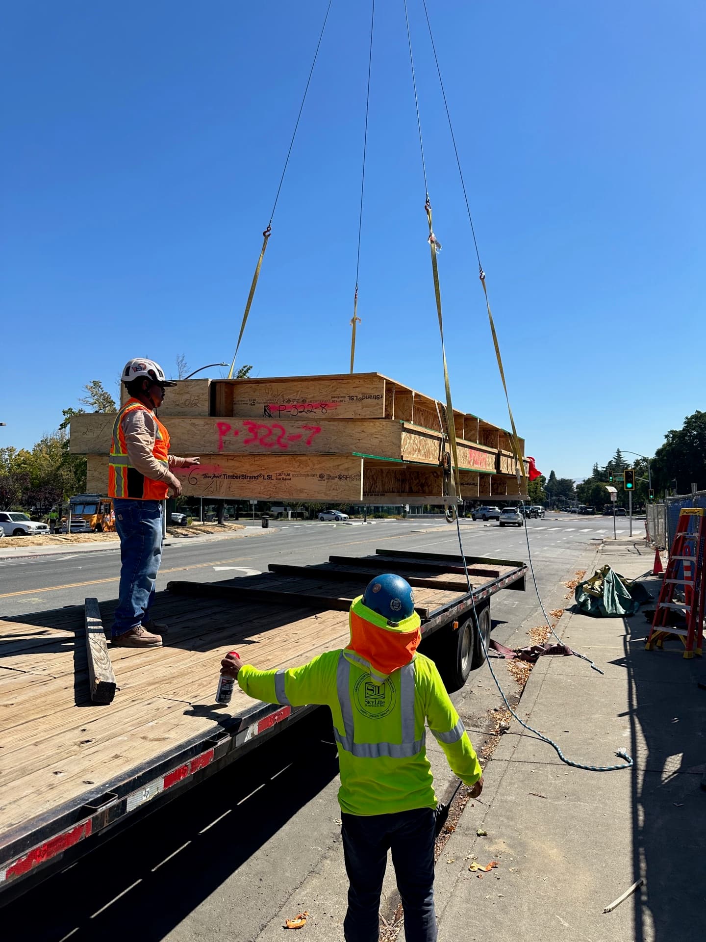 Workers guiding crane-lifted cassette panel into position