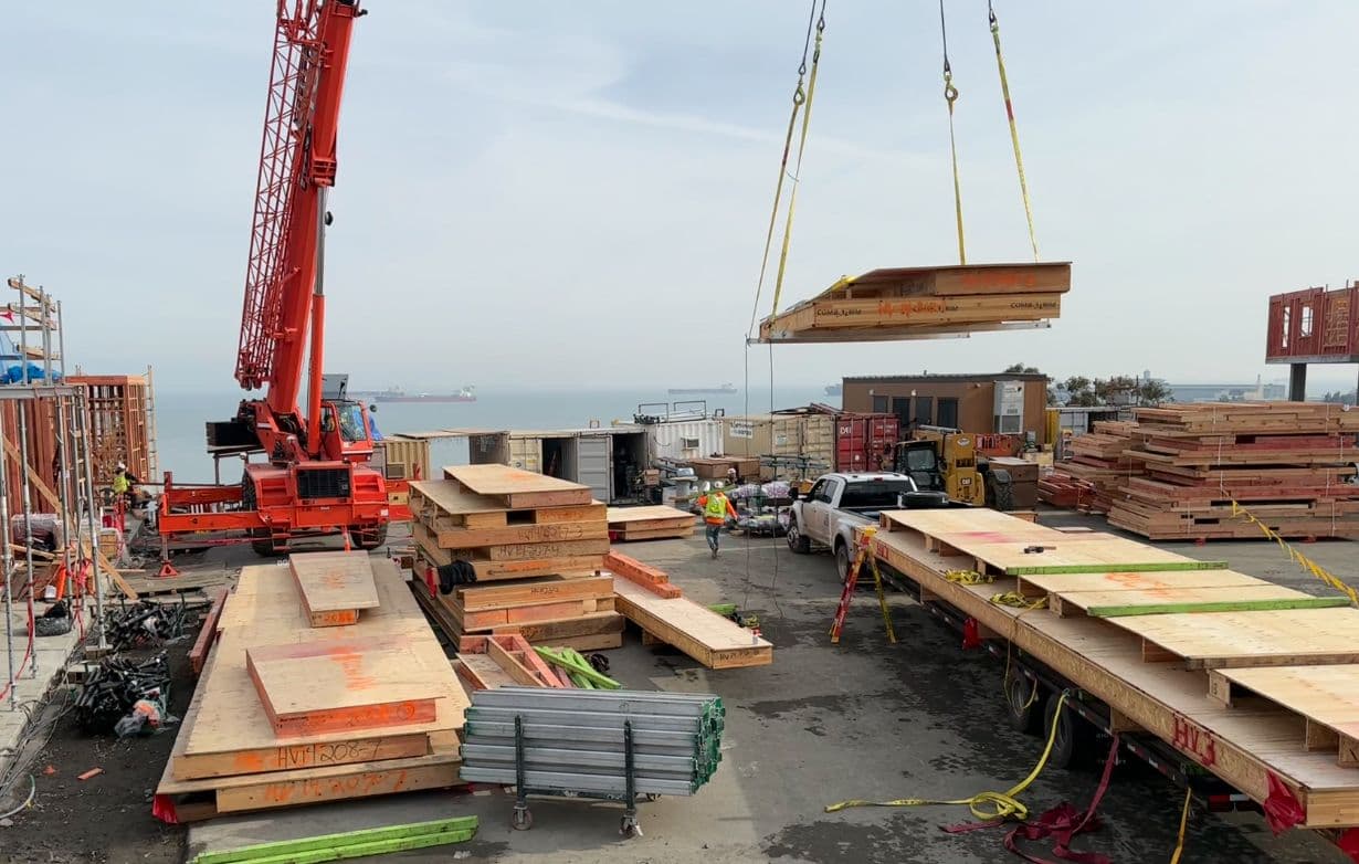 NCC crew operating crane to lift floor cassette at waterfront construction site